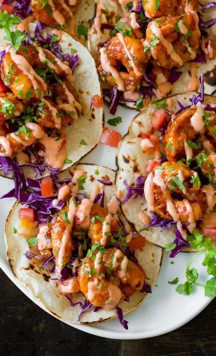Delicious Bang Bang Shrimp Tacos topped with creamy sauce and fresh garnishes.