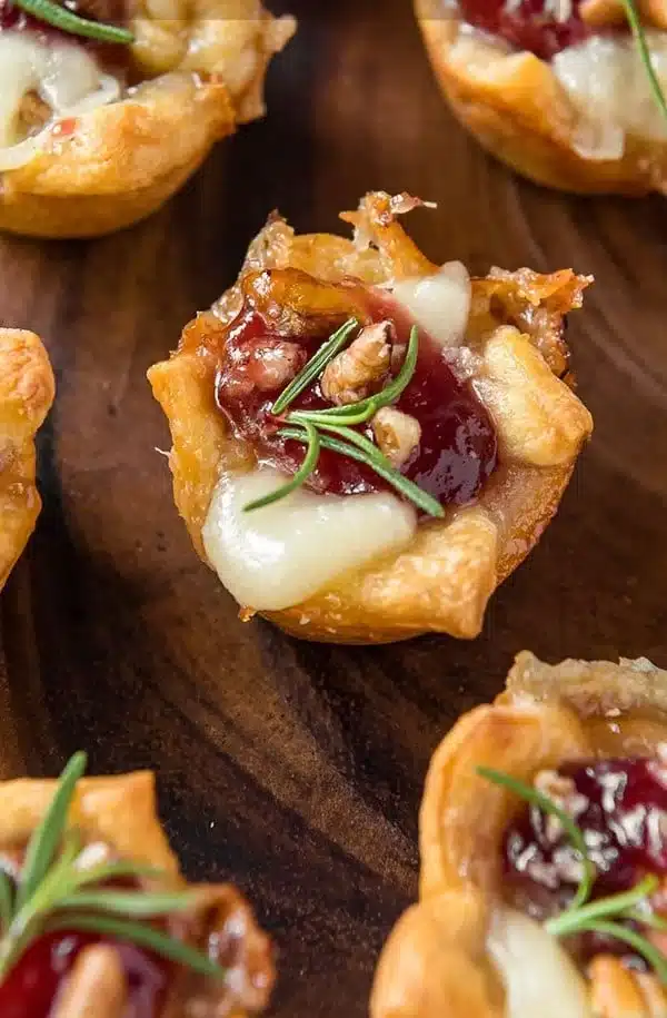 Cranberry Brie Bites on a serving platter, garnished with herbs.