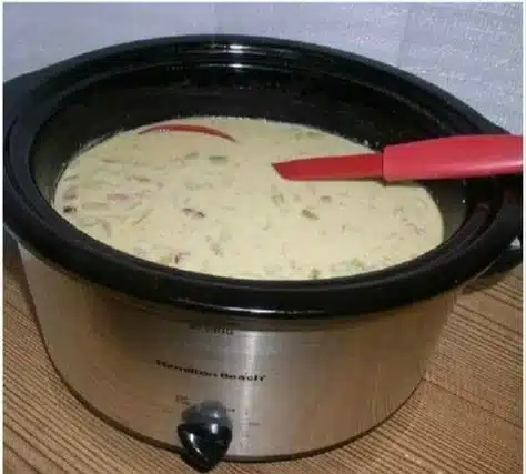 Bowl of homemade crockpot potato soup with ingredients displayed around it