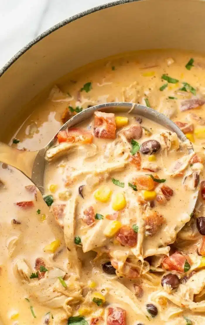 Delicious bowl of easy chicken taco soup garnished with cilantro and lime wedges.