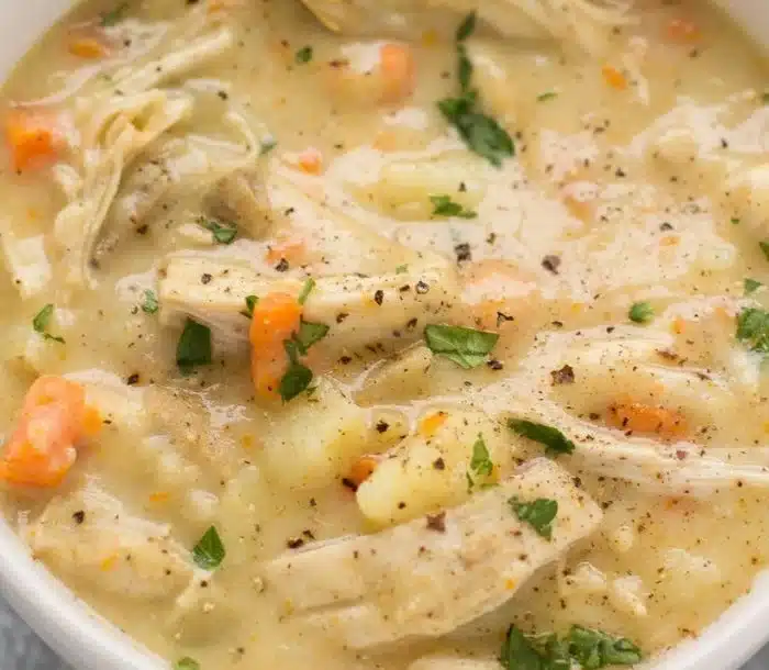 Protein-packed chicken pot pie soup in a bowl, garnished with herbs.