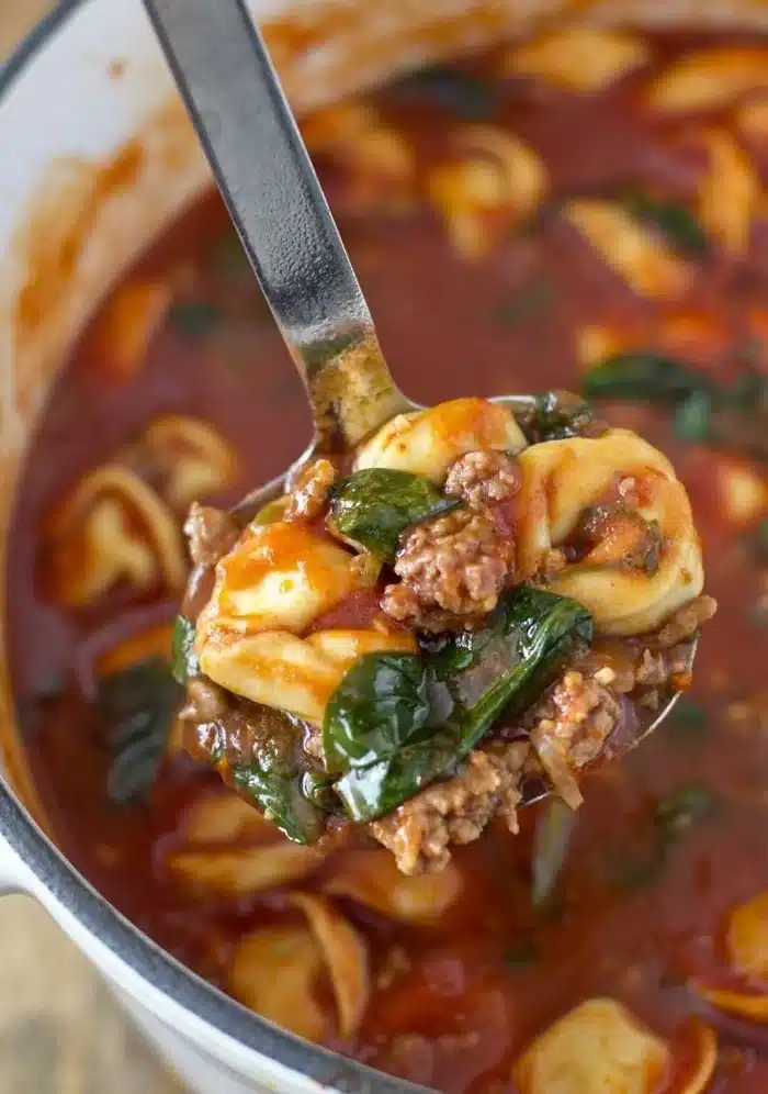 Bowl of Tortellini Soup with Italian sausage and spinach garnished with parsley