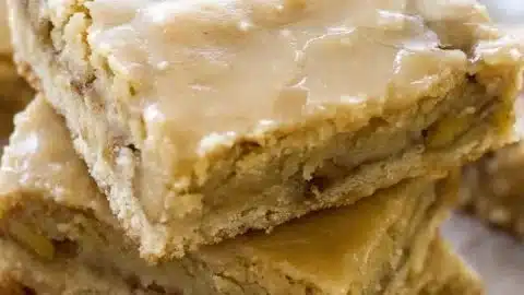 Delicious Apple Blondies topped with a rich Maple Glaze on a rustic wooden table.