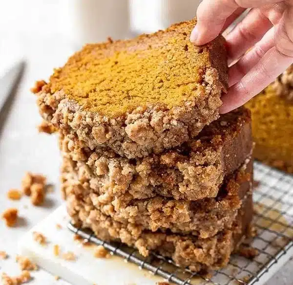 Slice of delicious pumpkin bread with spices and nuts on a wooden table.