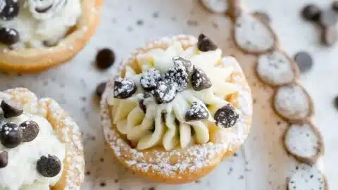 Delicious cannoli bites served on a plate with a dusting of powdered sugar.
