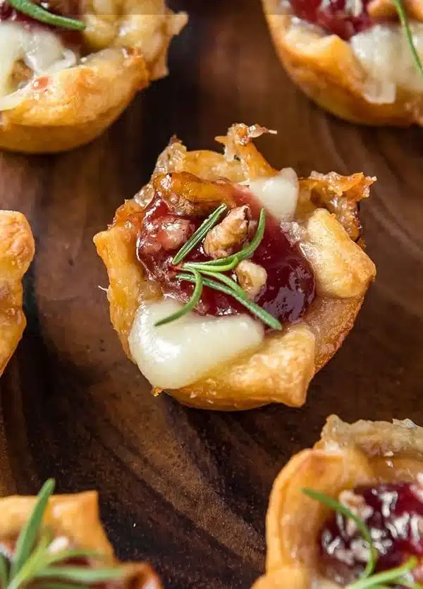 Plated cranberry brie bites with festive garnishes, perfect holiday appetizer.