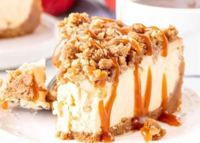 Slice of Easy Apple Crisp Cheesecake topped with apple crisp and caramel drizzle.