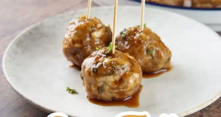 Savory apple cider meatballs in a rustic bowl, garnished with herbs.