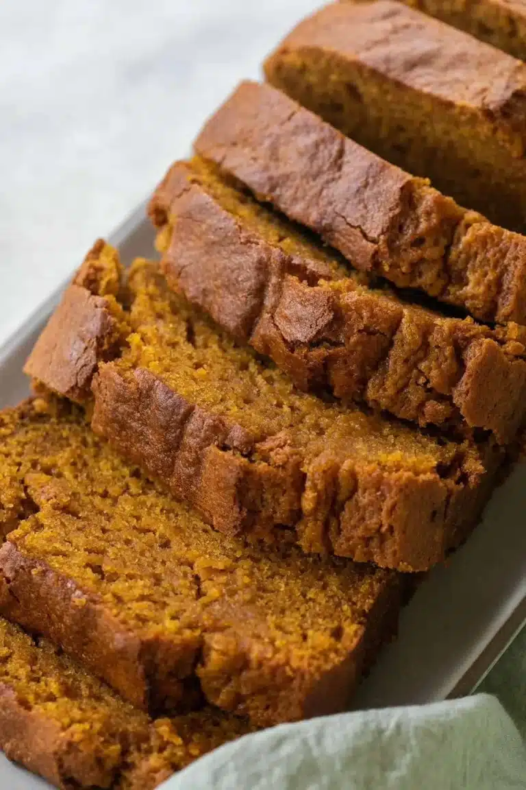 Sliced easy moist pumpkin bread on a wooden board, garnished with pumpkin seeds.