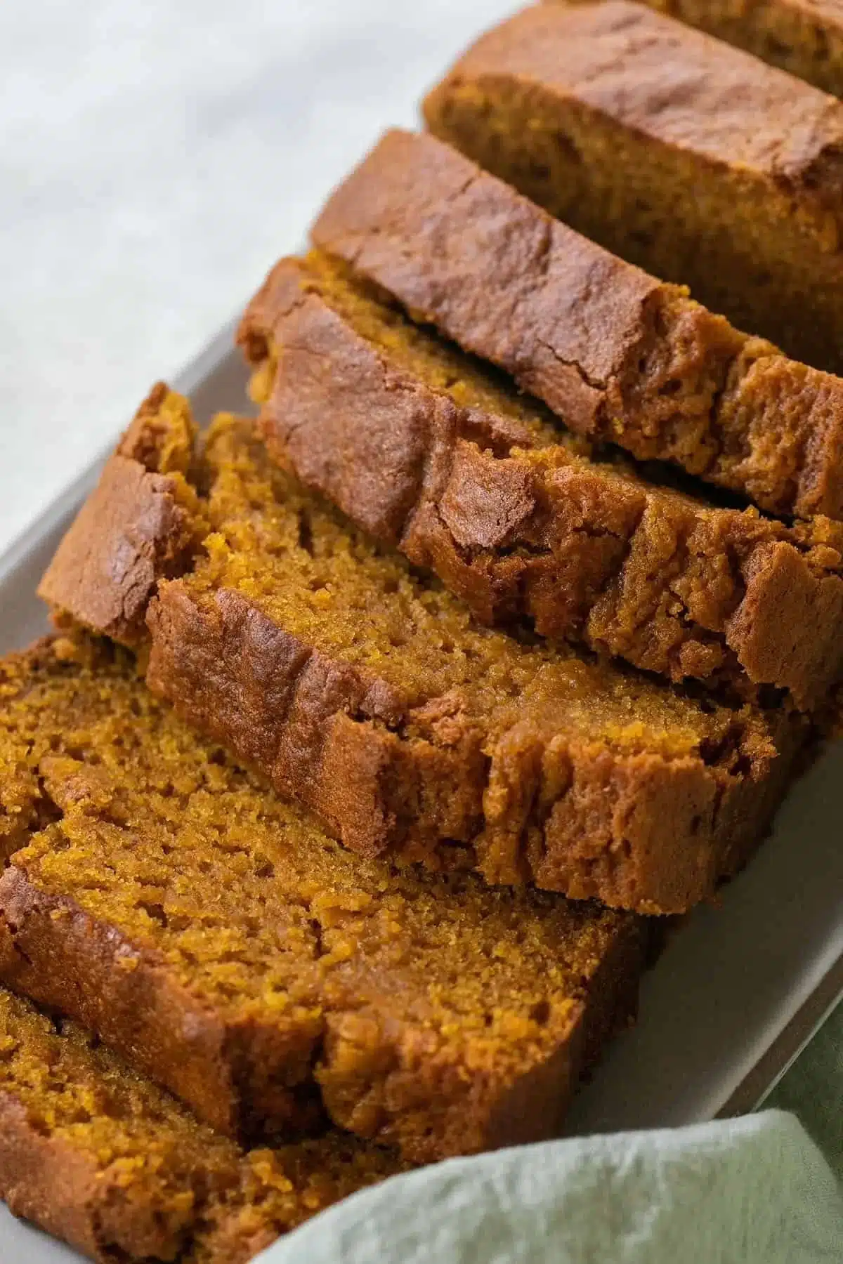 Sliced easy moist pumpkin bread on a wooden board, garnished with pumpkin seeds.