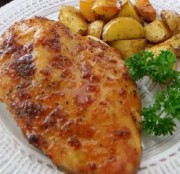 Sheet pan containing honey glazed chicken and potatoes ready to serve